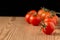 Close-up of a group of cherry tomatoes with selective focus, on wooden table, black background, horizontal,