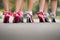 Close up of group of ladies wearing colourful bow heel shoes on tarmac