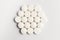 Close up of a group of white pills on white background, beautifully arranged as a hexagon, top view or flat lay