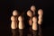 Close up of a  group of wooden pawns on a dark background.