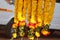 Close up of a groups of yellow marigolds flowers, red roses flowers, white jasmines flowers, and green leaves flowers chain