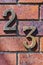 Close-up of grungy number 23 screwed onto distressed brick