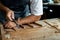 Close-up of guitar luthier using chisel to shave bracing of acoustic guitar