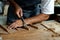 Close-up of guitar luthier using chisel to shave bracing of acoustic guitar