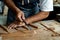 Close-up of guitar luthier using chisel to shave bracing of acoustic guitar