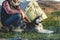 Close-up Guy bearded in jeans checkered shirt and a sleeveless jacket with a dog husk on vacation sitting on nature next