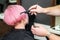 Close up of hairdresser is combing client`s pink hair in hair salon