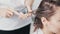 Close up of hairdresser hands applying hair mask on hair of young woman