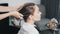 Close up of hairdresser hands applying hair mask on hair of young woman