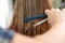 Close up of hairdresser hands cutting brown hair at home. Professional stylist trimming hair split ends