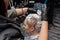 Close-up hairdresser\'s hands painting the client\'s head, hair, roots with a brush in a barbershop