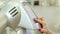 Close-up of a hairdresser switching on a professional hair dryer in a hair salon