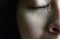 Close-up half face of Asian woman crying with tears, isolated on dark background. Concepts of emotion and expression of human