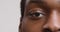Close up half face portrait of african american guy looking seriously at camera, blinking eye, white background