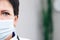 Close up half face portrait of Senior Family Medical Doctor in Face Mask. Successful Physician in White Lab Coat Looks