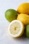 Close-up of half a lemon with lemons and limes, on white dishcloth, selective focus