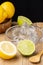 Close-up of half lemon, limes, wooden spoon, juicer and wooden bowl with lemons, black background,