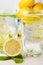 Close-up of half lemon and mint leaf with two glasses of water with lemon slices, lime and ice