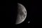 Close-up of half moon in the night sky with passing orbital space station ISS