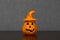 Close-up of Halloween pumpkin ornament with witch hat centered on wooden shelf