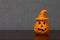 Close-up of Halloween pumpkin ornament with witch hat off-centered on wooden shelf