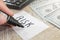 Close-up hand with a black marker writes the word `risk` on the background of dollars and a calculator.