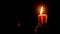 Close up hand burning match lights candle in darkness. Light fire wax candle burning in black darkness. Halloween