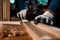 Close-up the hand of carpenter craftsman making pool cue or snooker cue with a manual hand wood planer in carpentry workplace.