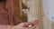 Close up of hand of caucasian woman touching golden necklaces hanging on rack, shopping for jewelry