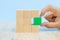 Close-up hand choose a green wooden block toy stacked in square shape without graphics for Business design concept and activity