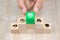 Close-up hand choose a green wooden toy blocks with protection icon for safety