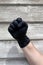 Close up of a hand fist with black medical protective gloves on wooden background