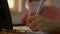 Close up hand of a girl wearing protective mask and writing on the desk with computer at home during COVID-19 outbreak situation.