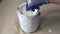 Close up of hand gloved painter mixing paint in metal paint can with wooden stick