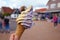 Close up of hand holding cone with mixed yellow and purple mango and berry soft serve ice cream with city scene in backgrou