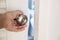 Close-up hand holding door knob, opening door slightly, selective focus