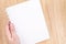 Close up Hand holding empty white open book above wood desk ,Mock up template for adding your content