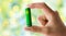 Close up of hand holding green alkaline battery