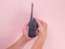 Close up hand holding portable walkie talkie isolated on pink background. Black handheld walkie talkie