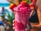 Close up of Hand Holding Refreshing Strawberry Smoothie with Fresh Berries on Top at the Beach