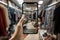 A close-up of a hand holding a smartphone, capturing a well-organized clothing store interior, showcasing the fusion of