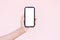 Close-up of hand holding smartphone with mockup. Pastel pink background.