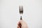 Close-up hand holding stainless fork on white background