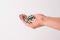 Close-up of a hand holding various capsules and medicines. White isolated background.