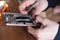 Close-up of the hand of a home craftsman repairing a disassembled smartphone. The concept of self-repair electronics at