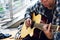 Close-up hand of homeless Asia man playing acoustic guitar on walking street.