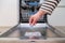 Close up of hand inserting soap capsule into dish washer in the kitchen. Person putting dish washing detergent into machine