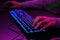 Close-up of a hand on a keyboard in neon color. Selective focus