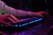 Close-up of a hand on a keyboard in neon color. Selective focus