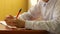 Close-up of the hand of a left-handed schoolboy learning to write. Caucasian left-handed child writes in a notebook doing homework